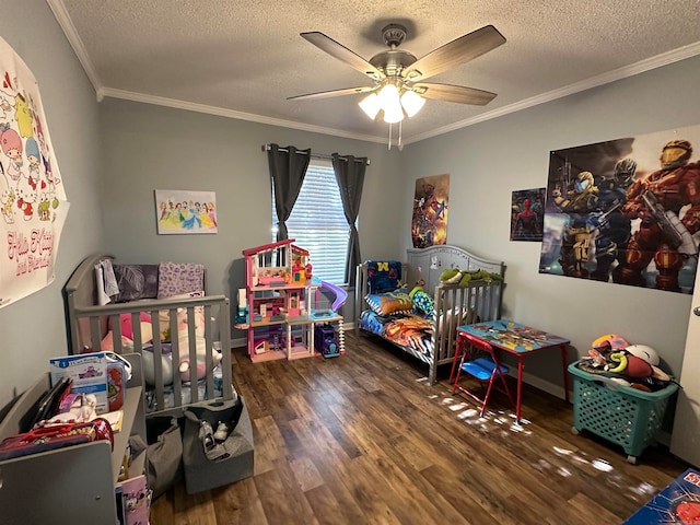 bedroom with dark wood-type flooring, a textured ceiling, ceiling fan, crown molding, and a nursery area