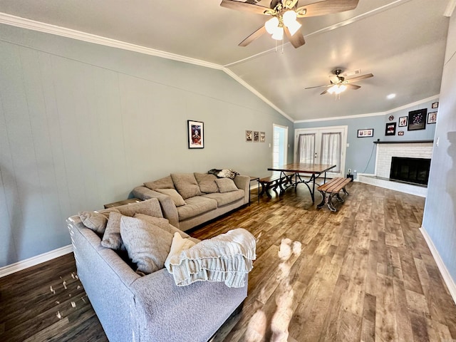 living room with vaulted ceiling, hardwood / wood-style floors, ceiling fan, crown molding, and a fireplace