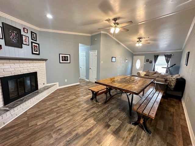 dining space with ornamental molding, ceiling fan, dark hardwood / wood-style floors, lofted ceiling, and a brick fireplace