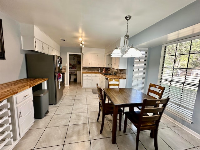 dining room featuring an inviting chandelier, sink, and light tile patterned floors