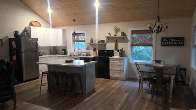 kitchen with plenty of natural light, stainless steel fridge, hanging light fixtures, and a breakfast bar area