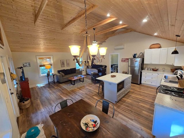 kitchen with stainless steel fridge, dark hardwood / wood-style flooring, lofted ceiling with beams, white cabinets, and hanging light fixtures