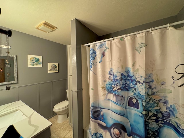 bathroom featuring curtained shower, vanity, toilet, and a textured ceiling