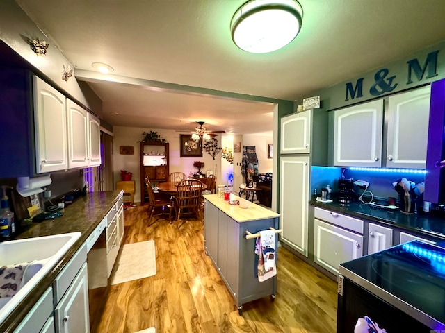 kitchen featuring light wood-type flooring, sink, white cabinets, ceiling fan, and a center island