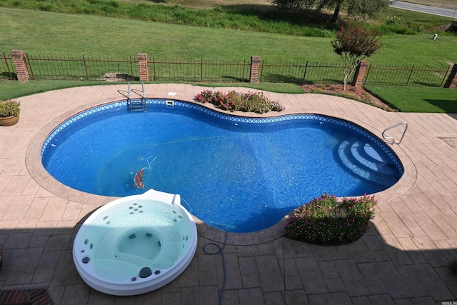 view of swimming pool with an outdoor hot tub, a yard, and a patio