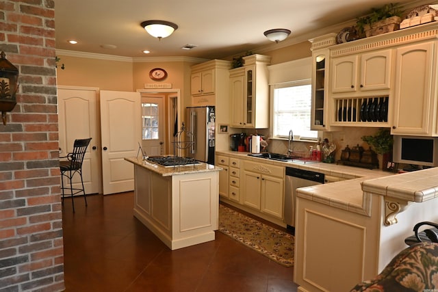 kitchen with appliances with stainless steel finishes, cream cabinets, tasteful backsplash, and a center island