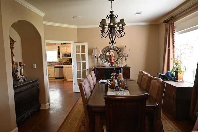 dining space with plenty of natural light, dark tile patterned floors, crown molding, and a notable chandelier