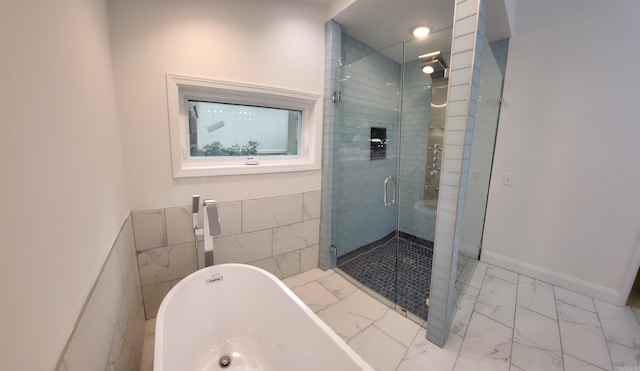 bathroom featuring shower with separate bathtub and tile walls