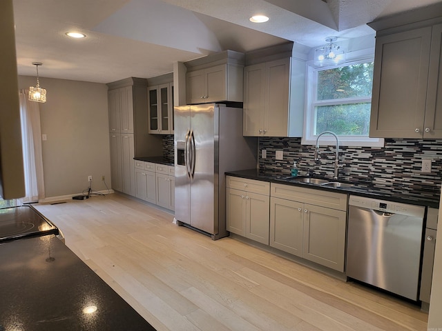 kitchen featuring light hardwood / wood-style floors, sink, gray cabinetry, backsplash, and appliances with stainless steel finishes