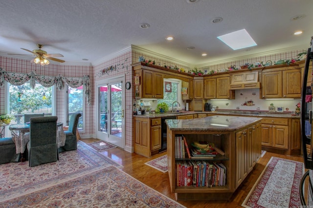 kitchen with a center island, hardwood / wood-style flooring, ceiling fan, crown molding, and a skylight