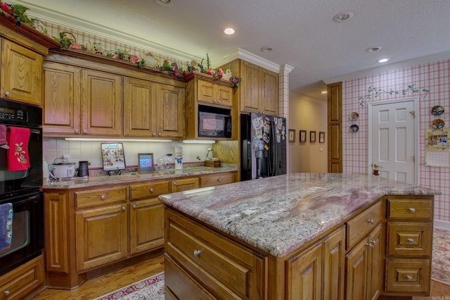 kitchen featuring light hardwood / wood-style floors, ornamental molding, black appliances, and a center island