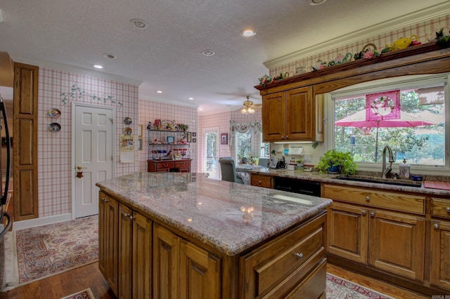 kitchen with light stone counters, a textured ceiling, sink, ceiling fan, and light wood-type flooring