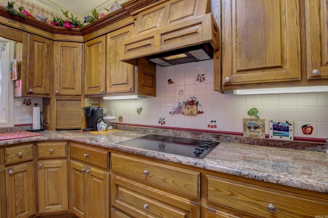 kitchen featuring backsplash, custom range hood, black electric stovetop, and light stone counters