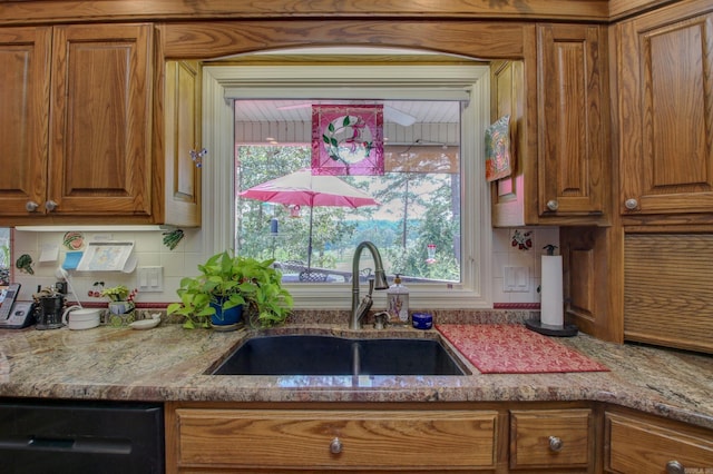 kitchen with black dishwasher, sink, light stone counters, and backsplash