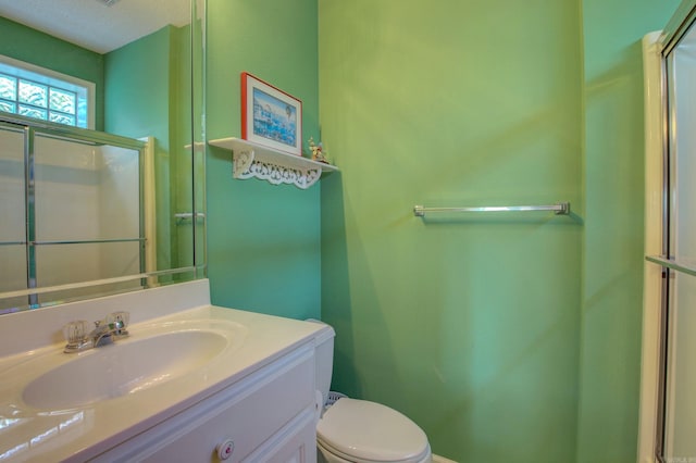 bathroom with vanity, a textured ceiling, toilet, and a shower with shower door