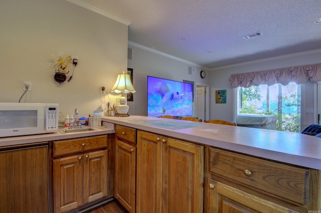 kitchen featuring kitchen peninsula, a textured ceiling, hardwood / wood-style flooring, sink, and crown molding