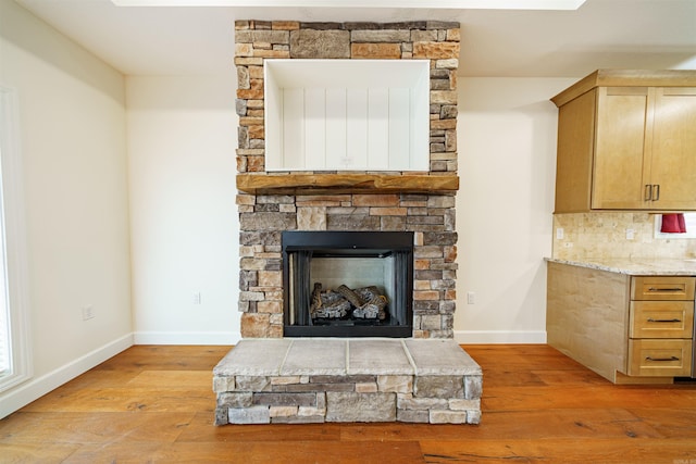 room details with a stone fireplace, tasteful backsplash, and wood-type flooring