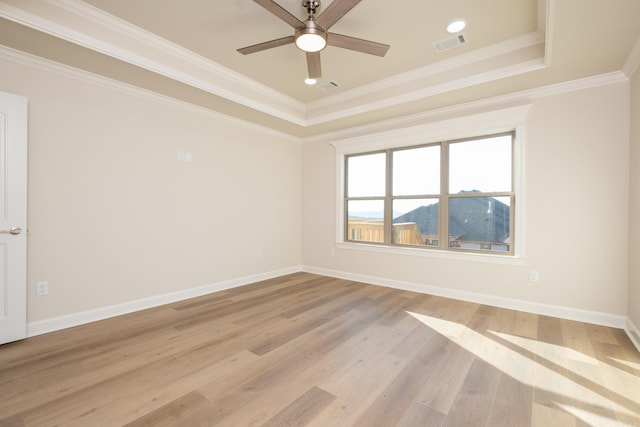 spare room featuring light wood-type flooring, a tray ceiling, ceiling fan, and ornamental molding