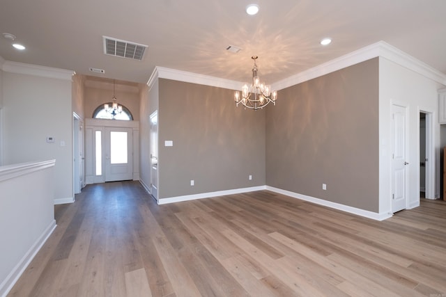 foyer entrance with ornamental molding, light hardwood / wood-style floors, and a notable chandelier