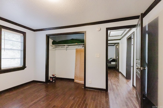 unfurnished bedroom featuring ornamental molding, a closet, a textured ceiling, and dark hardwood / wood-style floors