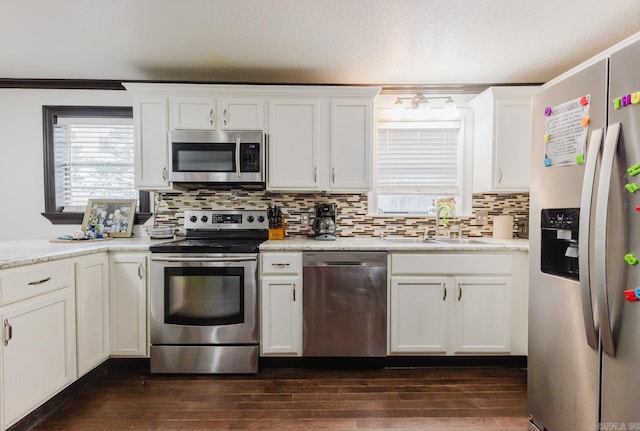 kitchen with stainless steel appliances, crown molding, white cabinets, dark wood-type flooring, and decorative backsplash