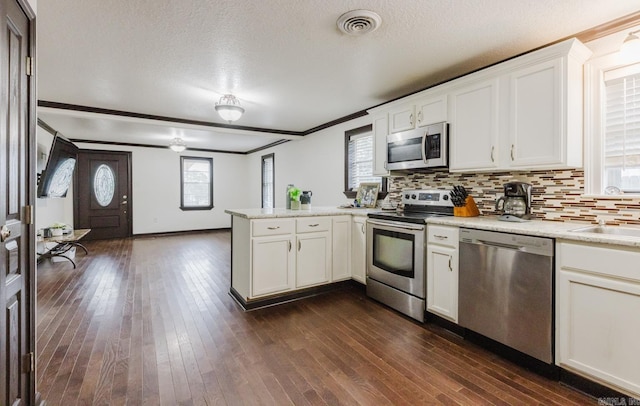 kitchen with stainless steel appliances, white cabinetry, dark wood-type flooring, and a textured ceiling