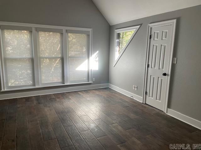 spare room with vaulted ceiling and dark hardwood / wood-style flooring