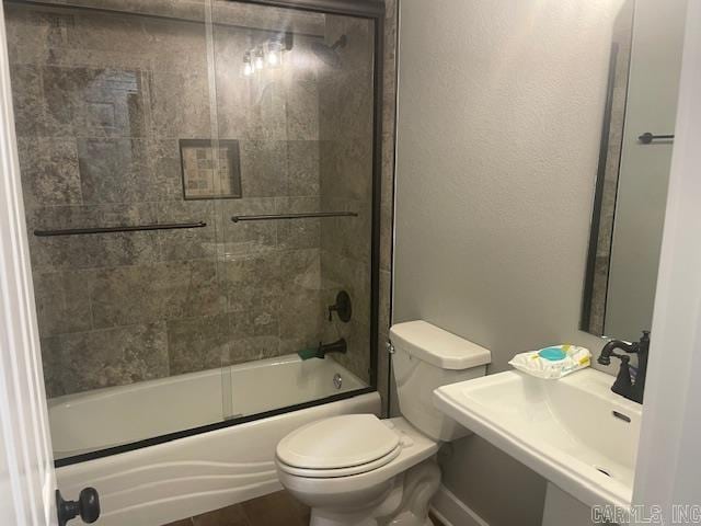 full bathroom with combined bath / shower with glass door, toilet, and sink