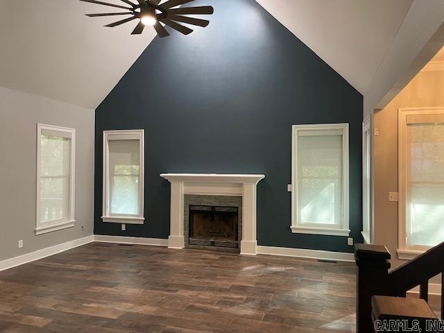 unfurnished living room featuring dark hardwood / wood-style flooring, ceiling fan, high vaulted ceiling, and a healthy amount of sunlight