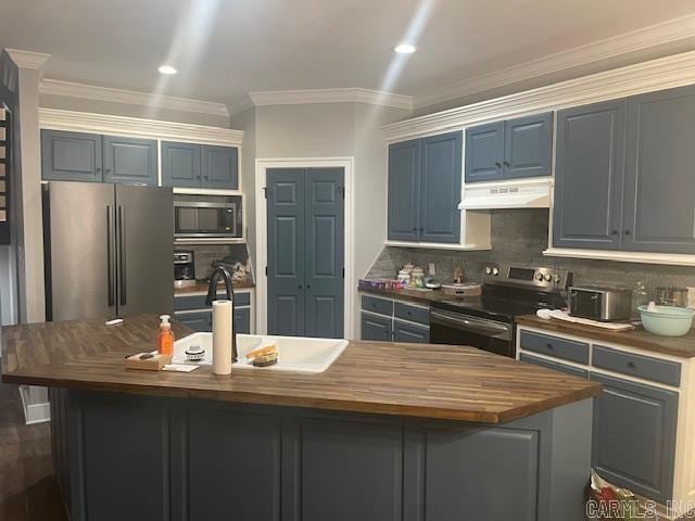 kitchen featuring butcher block counters, a kitchen island with sink, stainless steel appliances, and tasteful backsplash