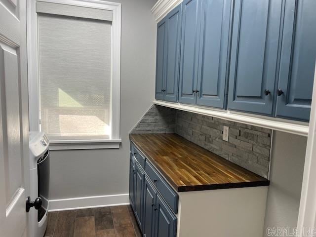 kitchen featuring blue cabinetry, dark hardwood / wood-style flooring, butcher block counters, and backsplash