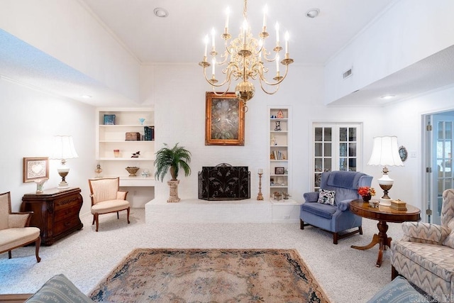 living room featuring crown molding, a brick fireplace, carpet flooring, built in shelves, and a chandelier