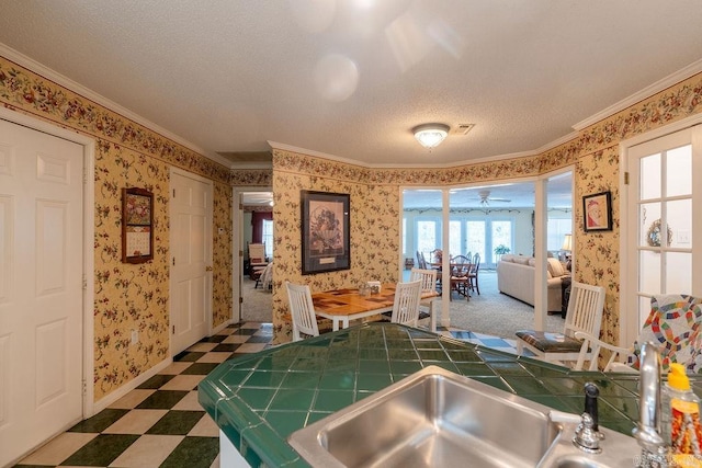 kitchen with a textured ceiling, tile counters, ceiling fan, and crown molding