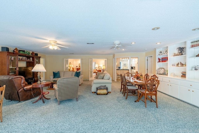 carpeted living room featuring ceiling fan and a textured ceiling