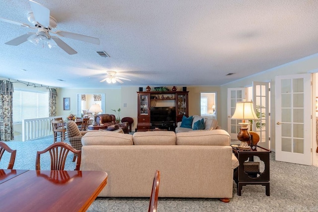 living room with light carpet, ceiling fan, and a textured ceiling