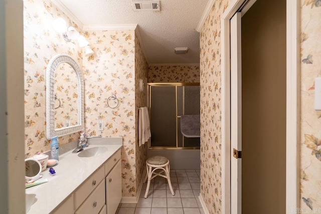 bathroom featuring vanity, crown molding, tile patterned flooring, enclosed tub / shower combo, and a textured ceiling