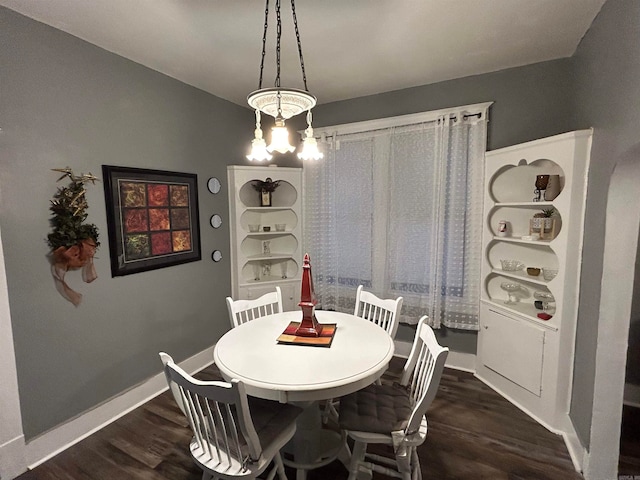 dining area with dark hardwood / wood-style floors and an inviting chandelier