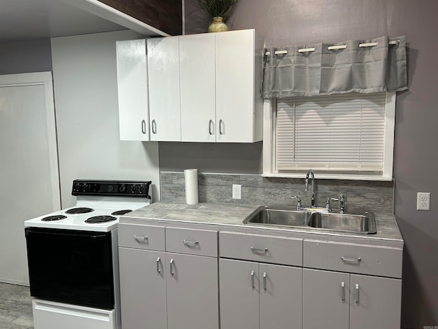 kitchen featuring white electric stove, tasteful backsplash, sink, and white cabinets