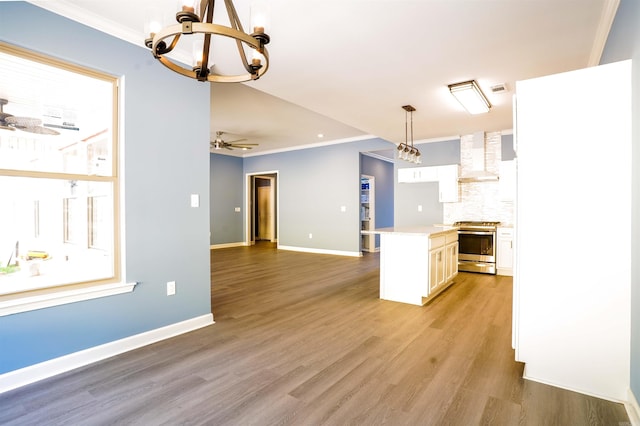 kitchen featuring wall chimney exhaust hood, hanging light fixtures, white cabinets, stainless steel stove, and light wood-type flooring