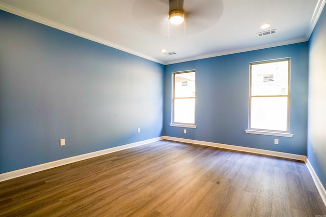 empty room featuring ornamental molding, a wealth of natural light, hardwood / wood-style flooring, and ceiling fan