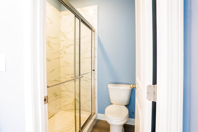 bathroom with wood-type flooring, toilet, and a shower with door