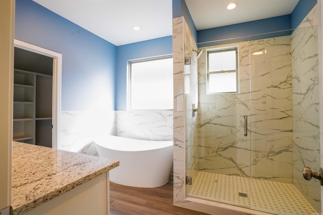 bathroom with wood-type flooring, plenty of natural light, and separate shower and tub