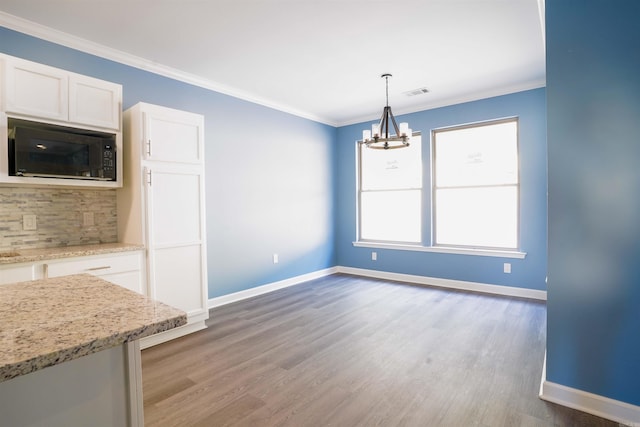 unfurnished dining area featuring hardwood / wood-style flooring, an inviting chandelier, and ornamental molding