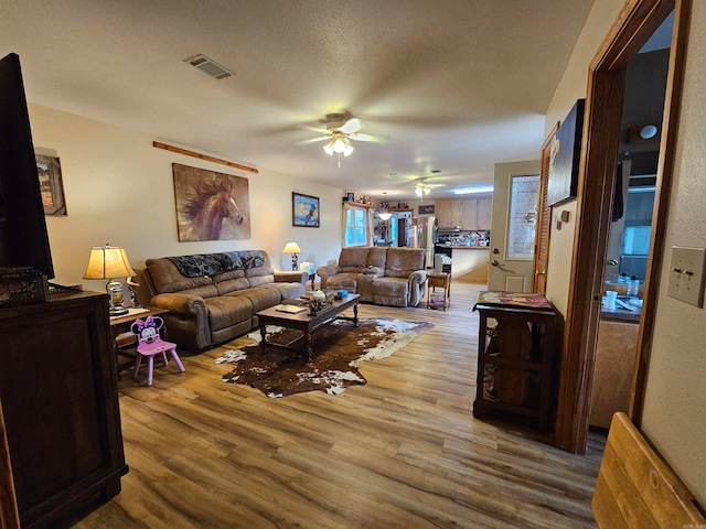 living room featuring a textured ceiling, hardwood / wood-style flooring, and ceiling fan