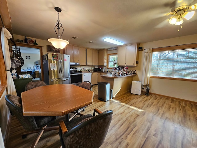 kitchen with light hardwood / wood-style floors, appliances with stainless steel finishes, ceiling fan, hanging light fixtures, and range hood