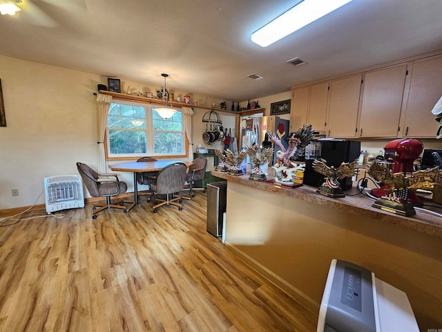 kitchen featuring pendant lighting, heating unit, stainless steel refrigerator, and light wood-type flooring