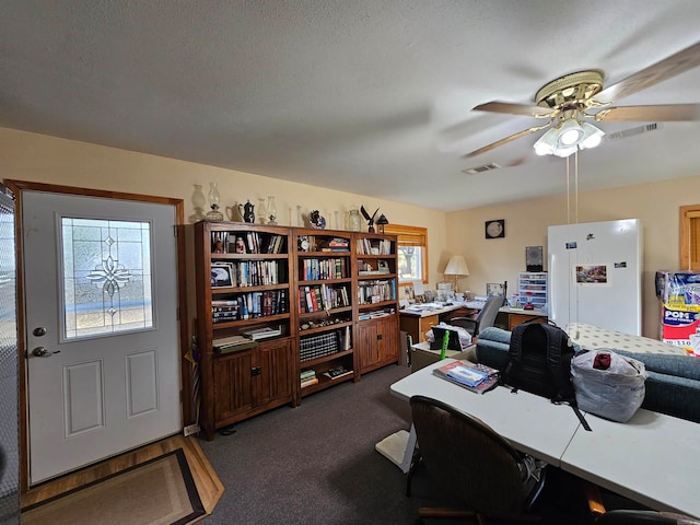 carpeted home office with a textured ceiling and ceiling fan