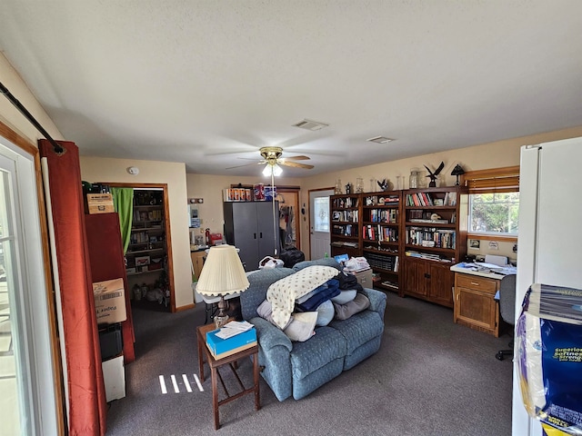 living room featuring ceiling fan and dark carpet