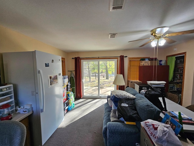 living room with a textured ceiling, ceiling fan, and carpet floors