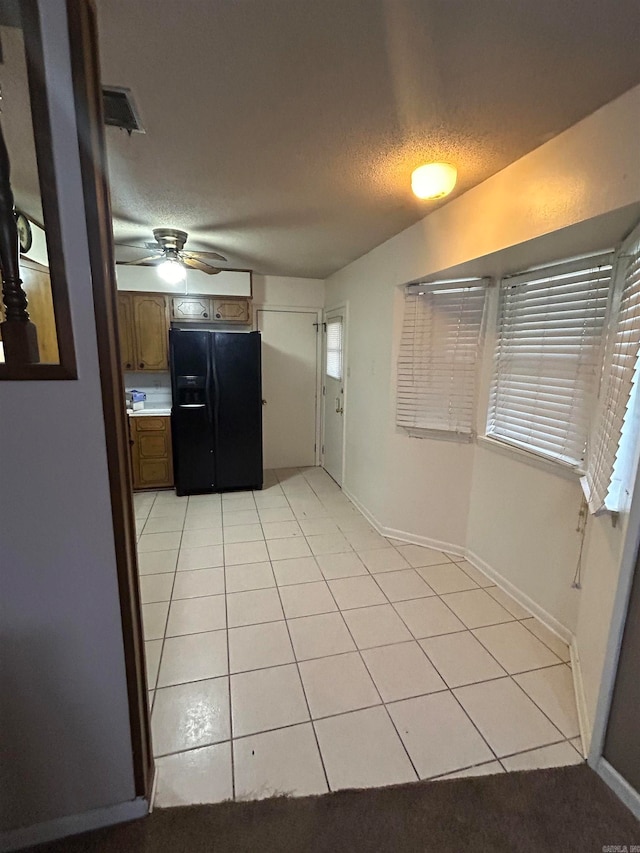 kitchen with a textured ceiling, black fridge with ice dispenser, light tile patterned flooring, and ceiling fan